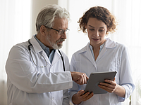 Medical team of two professional doctors talking using digital tablet